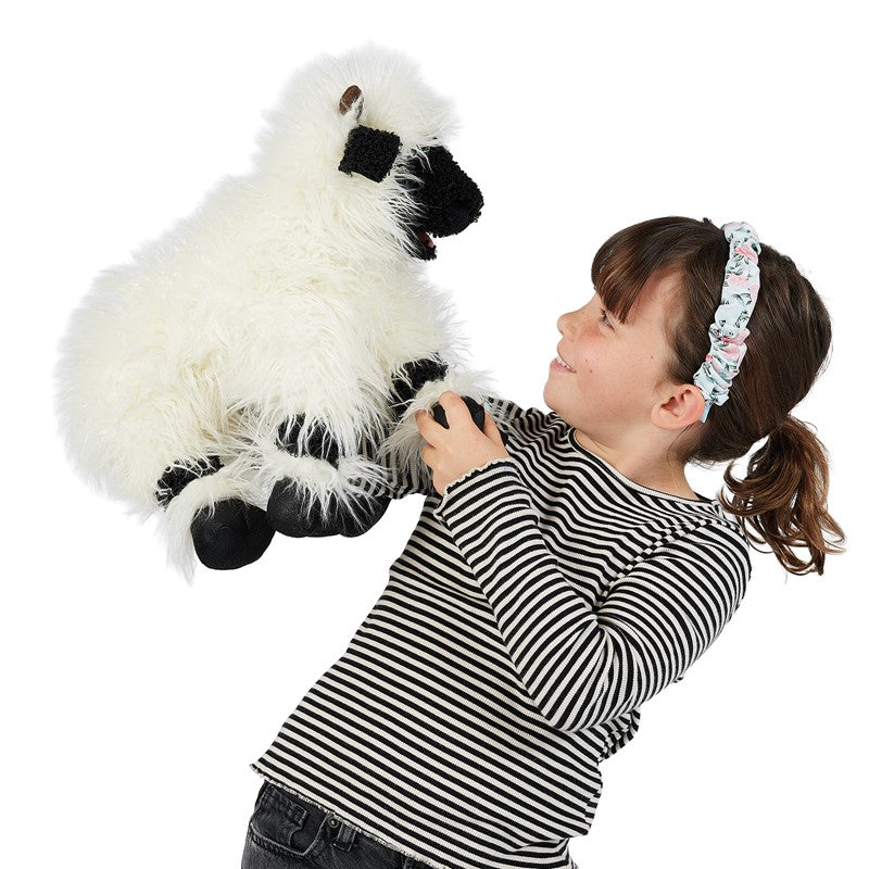 Child holding a plush sheep puppet on a white background