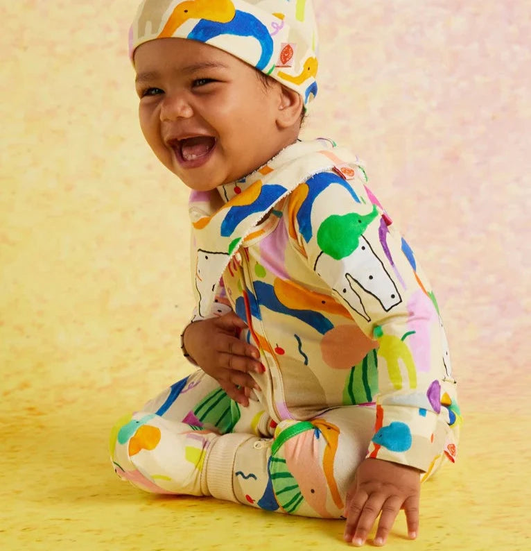 Baby wearing a colorful outfit with animal prints on a yellow background