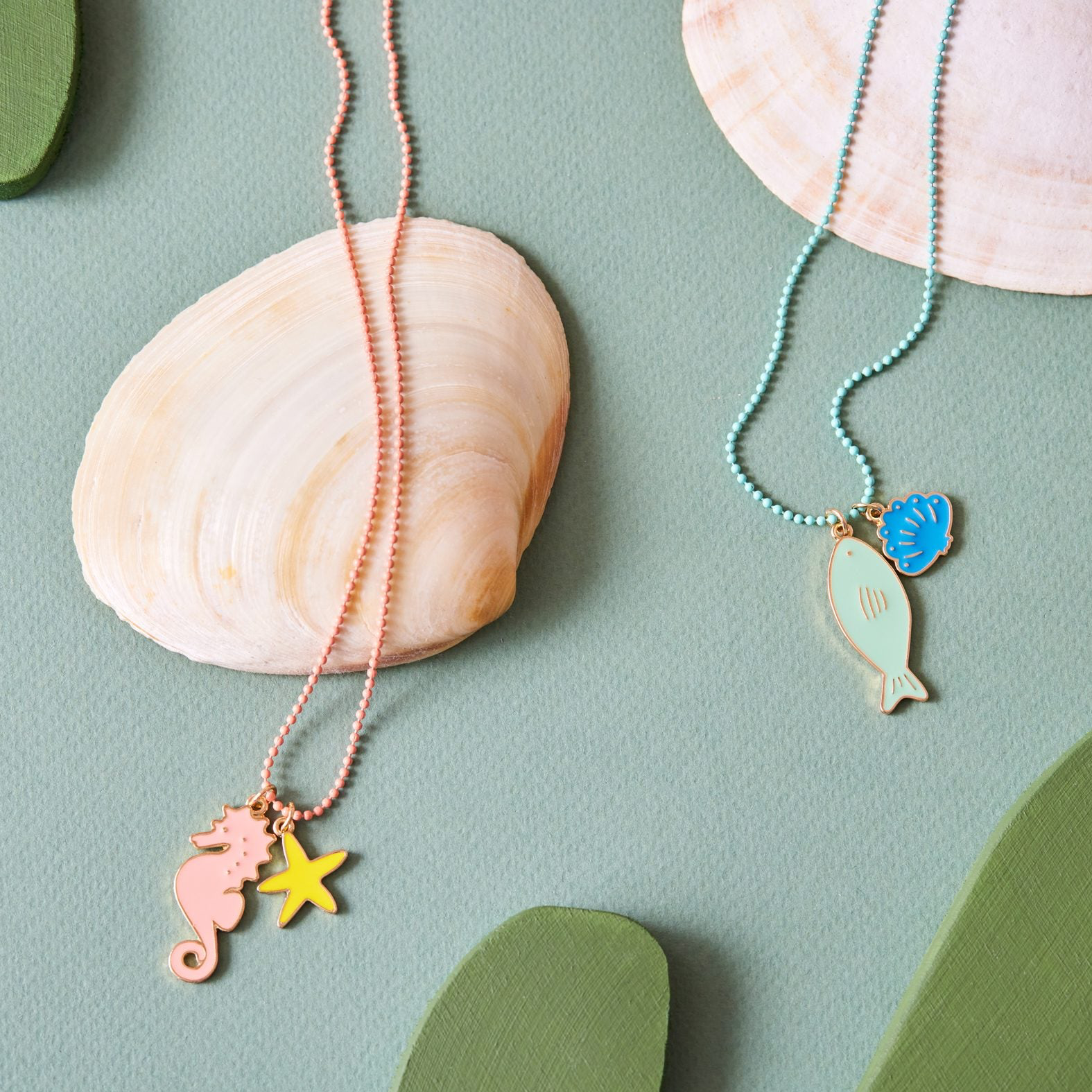 Seahorse and fish enamel necklace on a seashell display