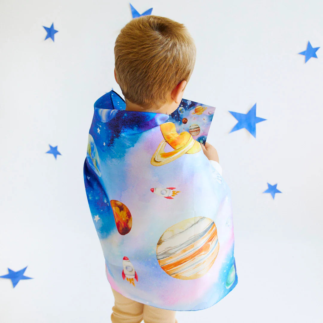 Child wearing a space-themed cape with stars on a white background