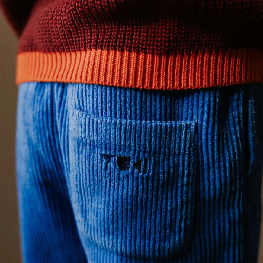 Blue corduroy pants with a red sweater collar on a blurred background