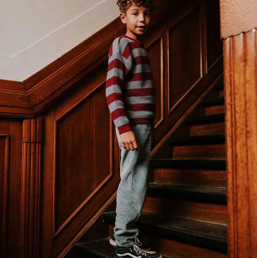 Child in a striped sweater standing on wooden stairs