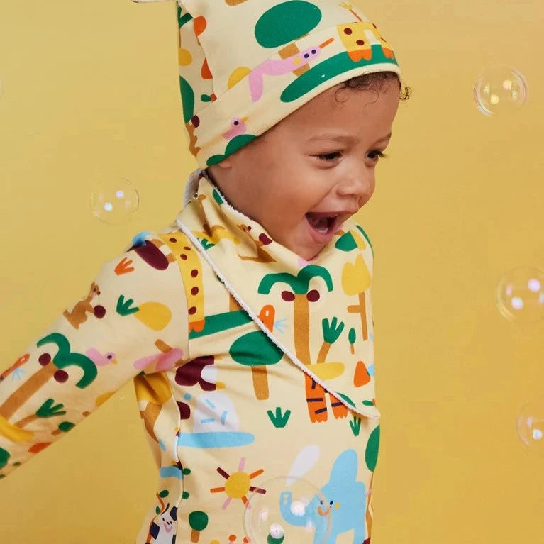 Child wearing a colorful outfit with animal patterns on a yellow background