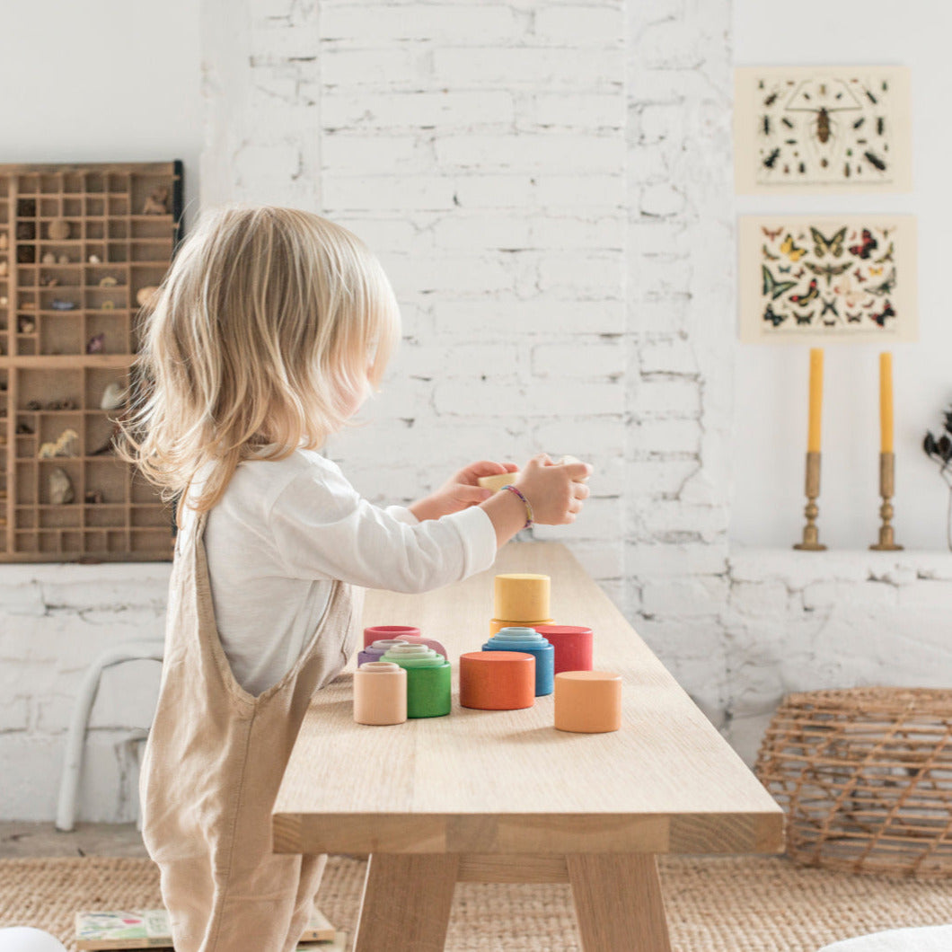 Child playing with colorful wooden bowls with a playroom back ground