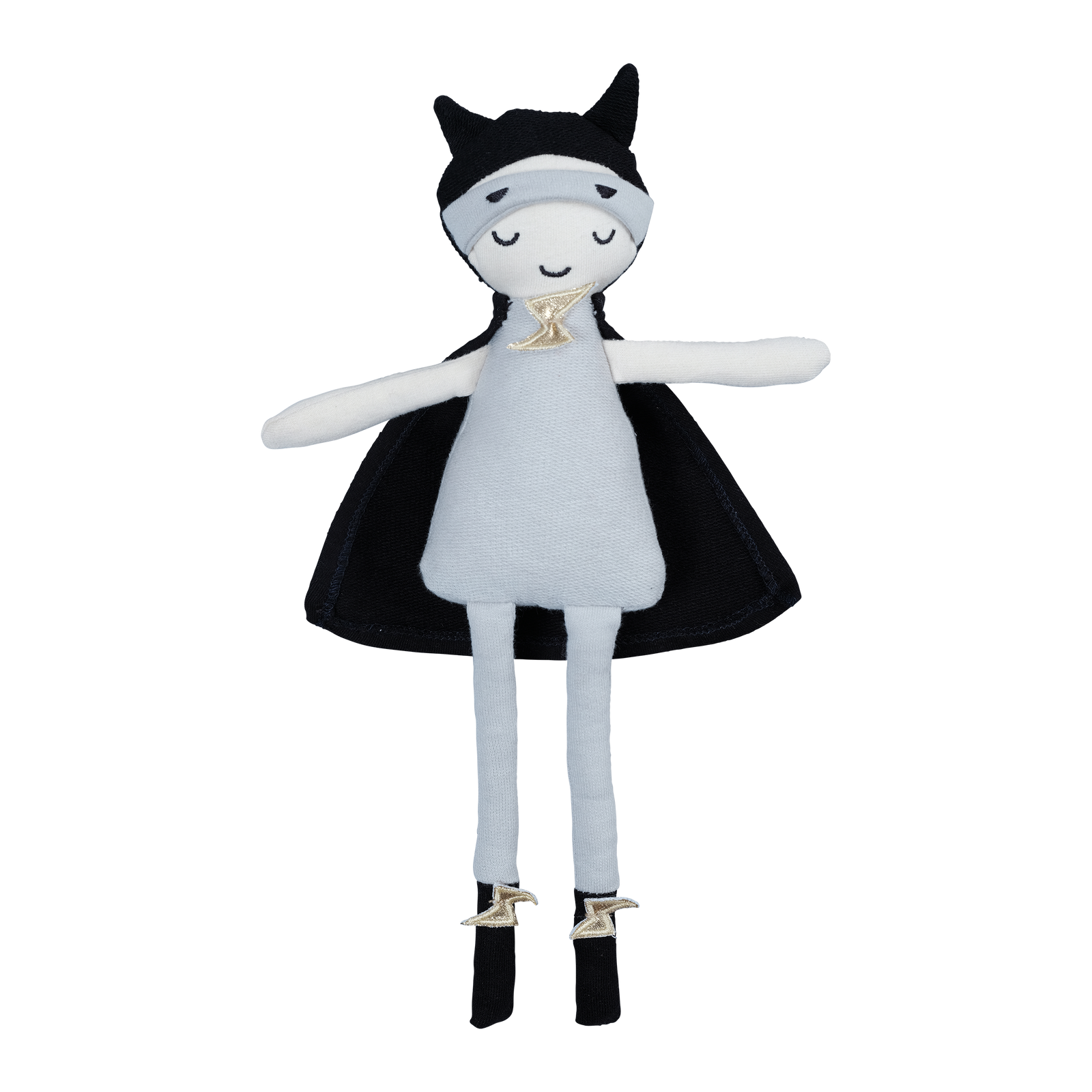 A toy doll dressed as a superhero with a black cape and white costume, perched on a stone surface.